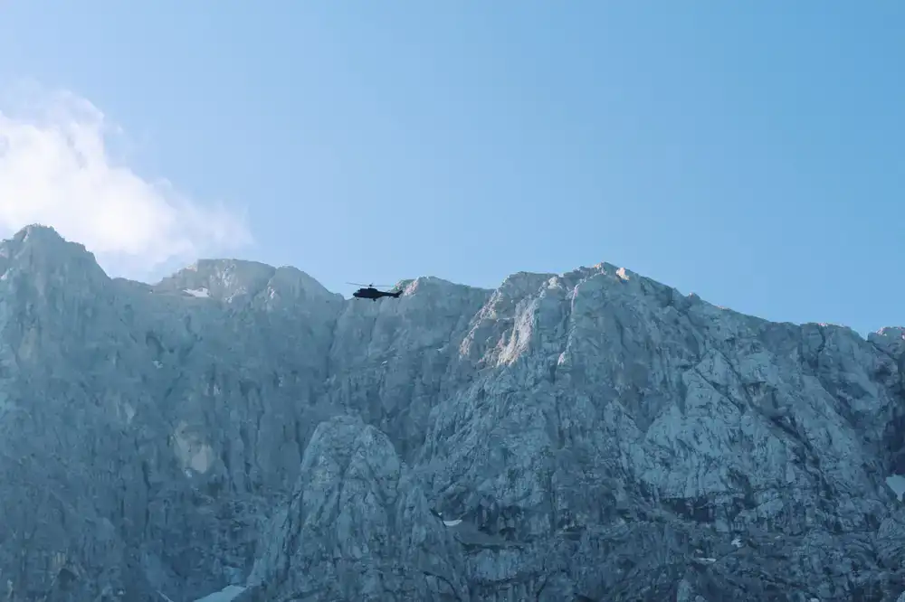 Helicopter soaring over rugged alpine peaks