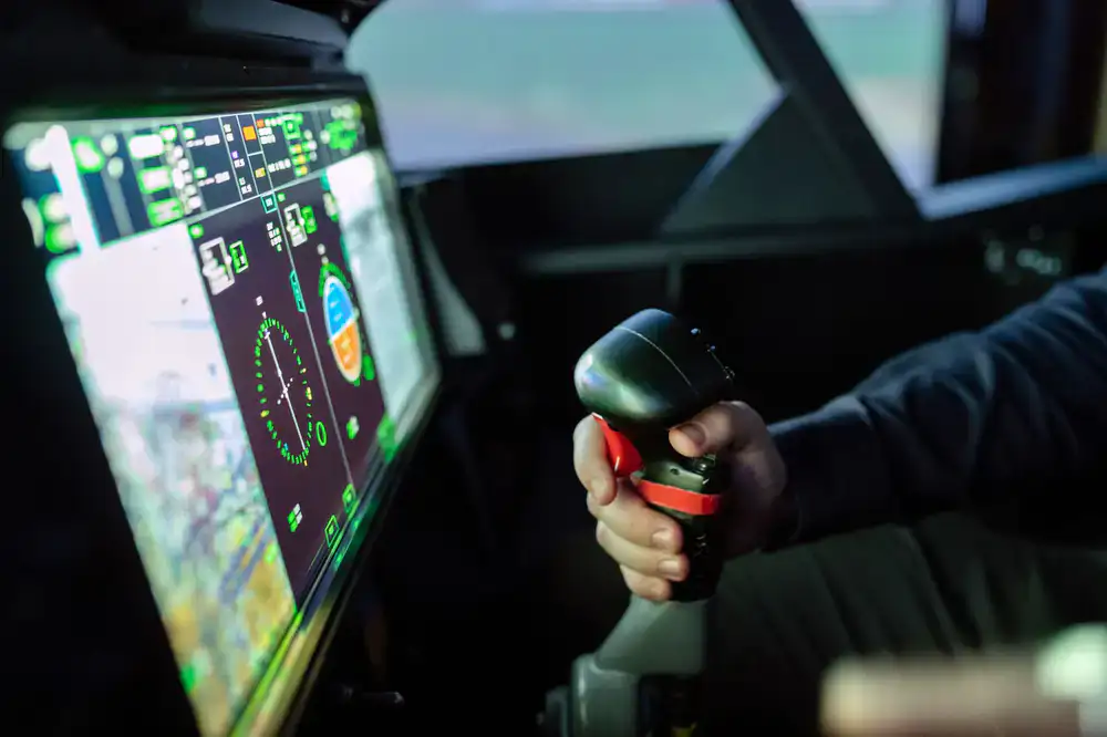 Instructor pointing out controls to a new pilot in the simulator